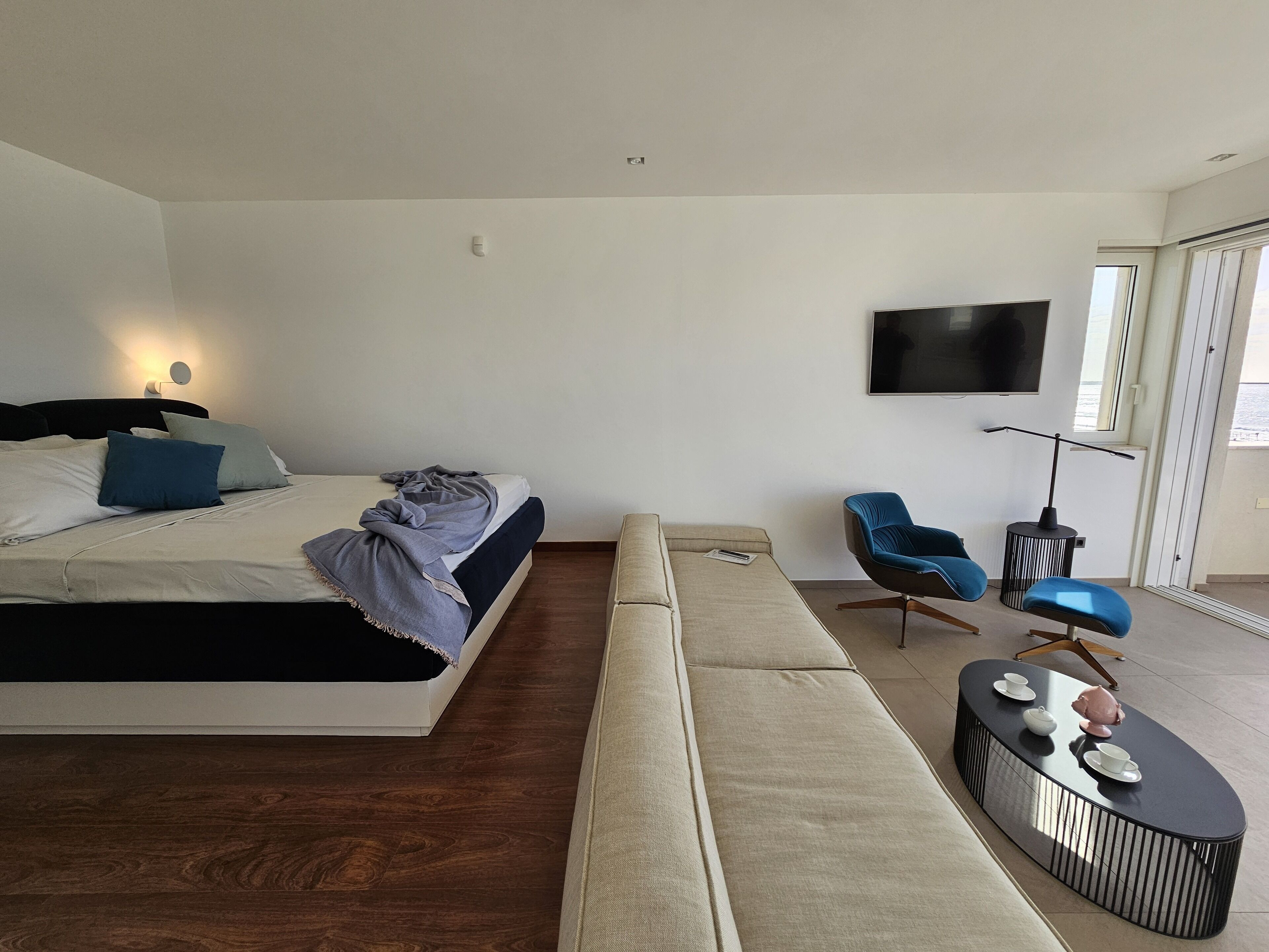 A modern bedroom with a bed, a sofa, a TV, and a coffee table.
