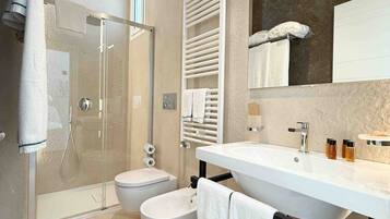 A modern bathroom with a glass-enclosed shower, a white sink, and a toilet.