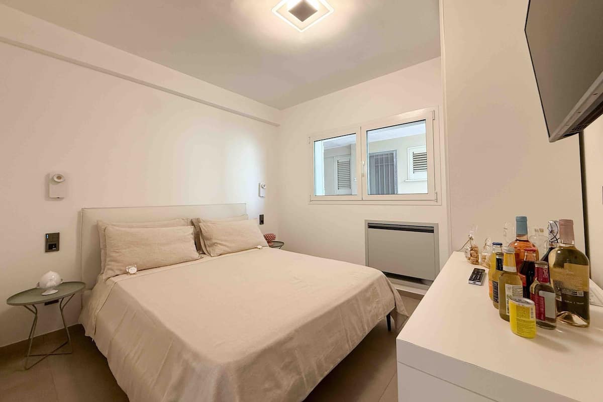 Une chambre à coucher avec un lit, une petite table, une télévision et une fenêtre.