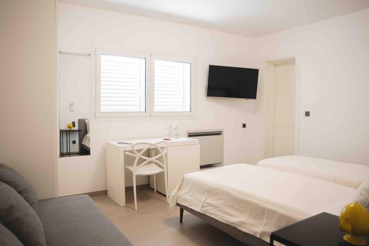 Une chambre à coucher avec un lit, un bureau, une chaise, une télévision et une fenêtre.