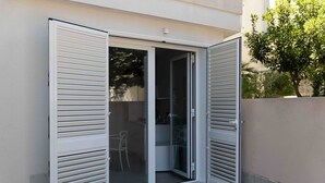 Une porte-fenêtre coulissante donnant sur un espace extérieur aménagé avec une chaise et une table.