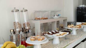 A buffet with various food items, including pastries and desserts, arranged on white stands.