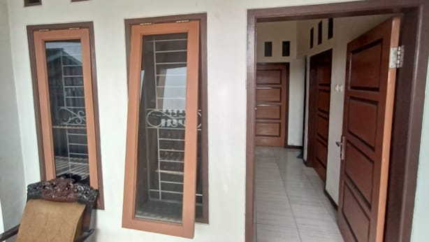 Un couloir avec des portes en bois et une porte en verre munie d’une grille métallique.