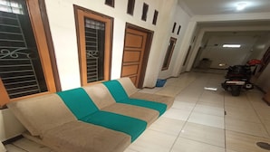 Un salon avec un canapé beige et turquoise, des portes en bois et un sol carrelé.
