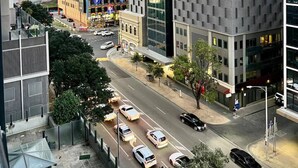 A modern urban street with high-rise buildings, a colorful building with a unique facade, and a road with cars.