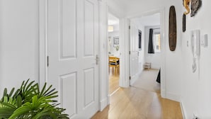 Un couloir avec des portes blanches, un plancher en bois et un luminaire suspendu.