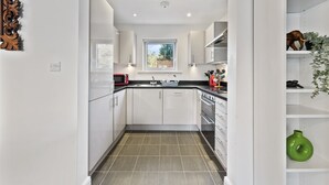 Une cuisine moderne avec des meubles blancs, un plan de travail noir et une fenêtre au-dessus de l’évier.