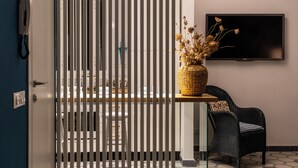 Una habitación con comedor, un televisor montado en la pared, una cesta de mimbre sobre una mesa y una silla de mimbre.