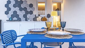 Un comedor con una mesa azul, armarios blancos y una pared de azulejos hexagonales.