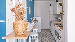 Una cocina moderna con una pared azul de acento, muebles blancos, encimera de madera y una cesta de mimbre con flores secas.
