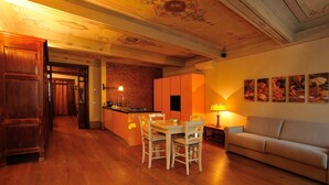 A cozy kitchen with wooden flooring, a dining table with chairs, a sofa, and a kitchen island. - Orfeo's House (Modena)