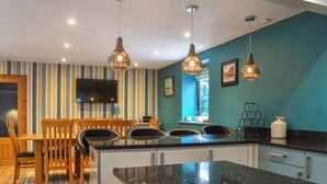 A modern kitchen with a large island, striped wallpaper, and pendant lighting. - 3 bedroom accommodation in Whitby (Whitby)