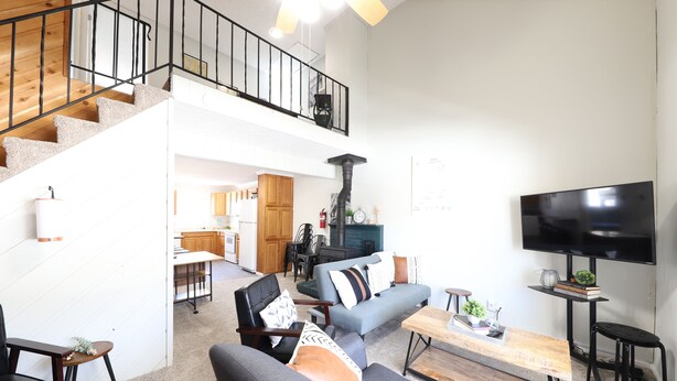 Un salón amplio con una escalera, un televisor de pantalla plana y una zona de estar acogedora.
