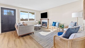 A modern living room with a fireplace, a sofa, a chair, and a TV mounted on the wall. - Boho Hillside Retreat In Boises Northend (Boise)