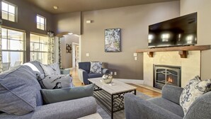 A spacious living room with a fireplace, a flat-screen TV mounted above it, and a large window providing natural light. - Dog Friendly Cozy Quiet Eagle ID Home sleeps 6 (Eagle)