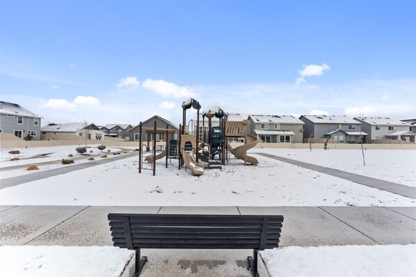 A playground with slides and climbing structures in a snowy residential area. - Beautiful 3 Bedroom Home in Meridian (Meridian)