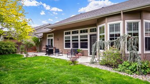 Une maison d’habitation dotée d’un patio couvert, d’un barbecue et d’un jardin bien entretenu.