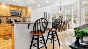 Une cuisine moderne avec des meubles en bois, un îlot central et des tabourets de bar noirs.