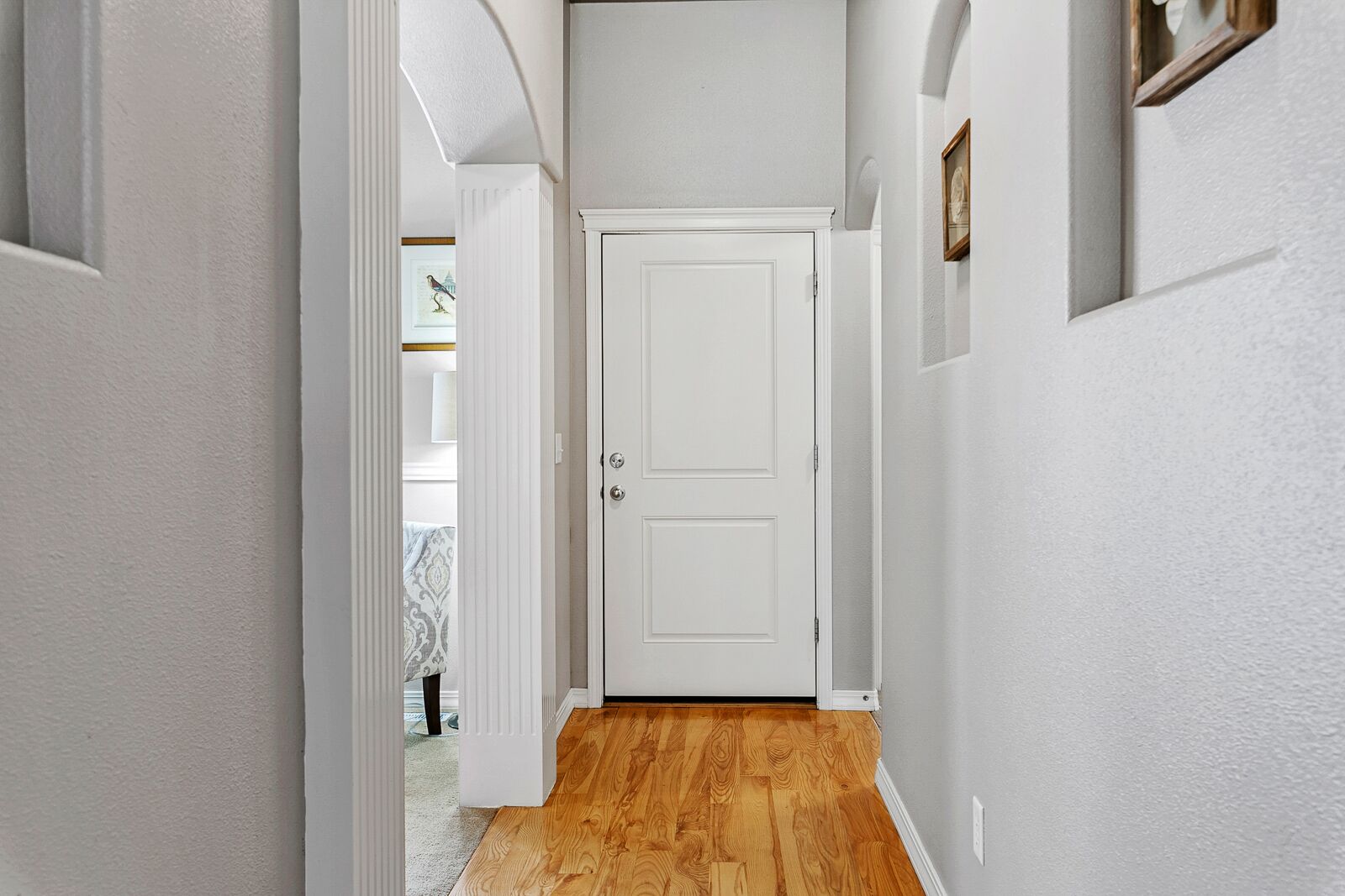 A hallway with a wooden floor and a white door.