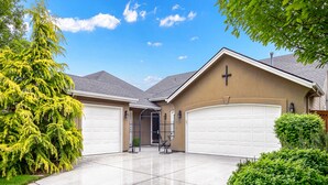Une maison à deux étages avec un garage, une croix sur le mur avant et une pelouse bien entretenue.