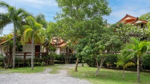 A pathway leading to a building with multiple rooms, surrounded by lush greenery and palm trees. - Lanta School Beach Resort (Ko Lanta)