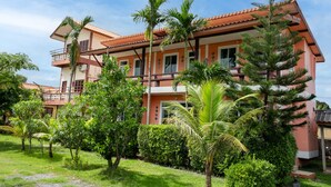 A multi-story building with a red-tiled roof, surrounded by lush greenery and palm trees. - Lanta School Beach Resort (Ko Lanta)