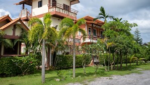 A multi-story building with a balcony, surrounded by lush greenery and palm trees. - Lanta School Beach Resort (Ko Lanta)