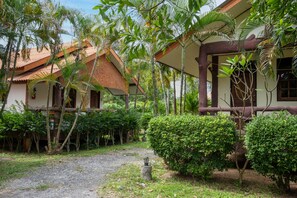 A traditional house with a thatched roof, surrounded by lush greenery and a gravel path. - Lanta School Beach Resort (Ko Lanta)