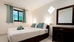A bedroom with a bed, a desk, a chair, a window with curtains, a mirror, and a small skylight. - Lanta School Beach Resort (Ko Lanta)