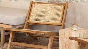 Ein Holzstuhl mit einem gewobenen Rücken, eine gepolsterte Bank und ein kleiner Holztisch mit einer Kerze.