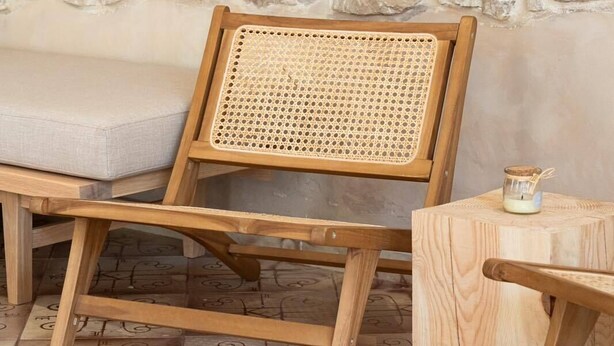 A wooden chair with a woven backrest, a cushioned bench, and a small wooden table with a candle. - ERAMAI  (Patras)