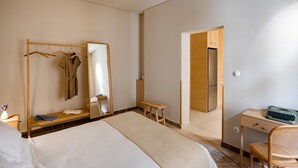 A hotel room with a bed, a wooden desk, a chair, a mirror, and a wardrobe. - ERAMAI  (Patras)