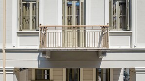 A building with a balcony featuring ornate metal railings and shutters. - ERAMAI  (Patras)