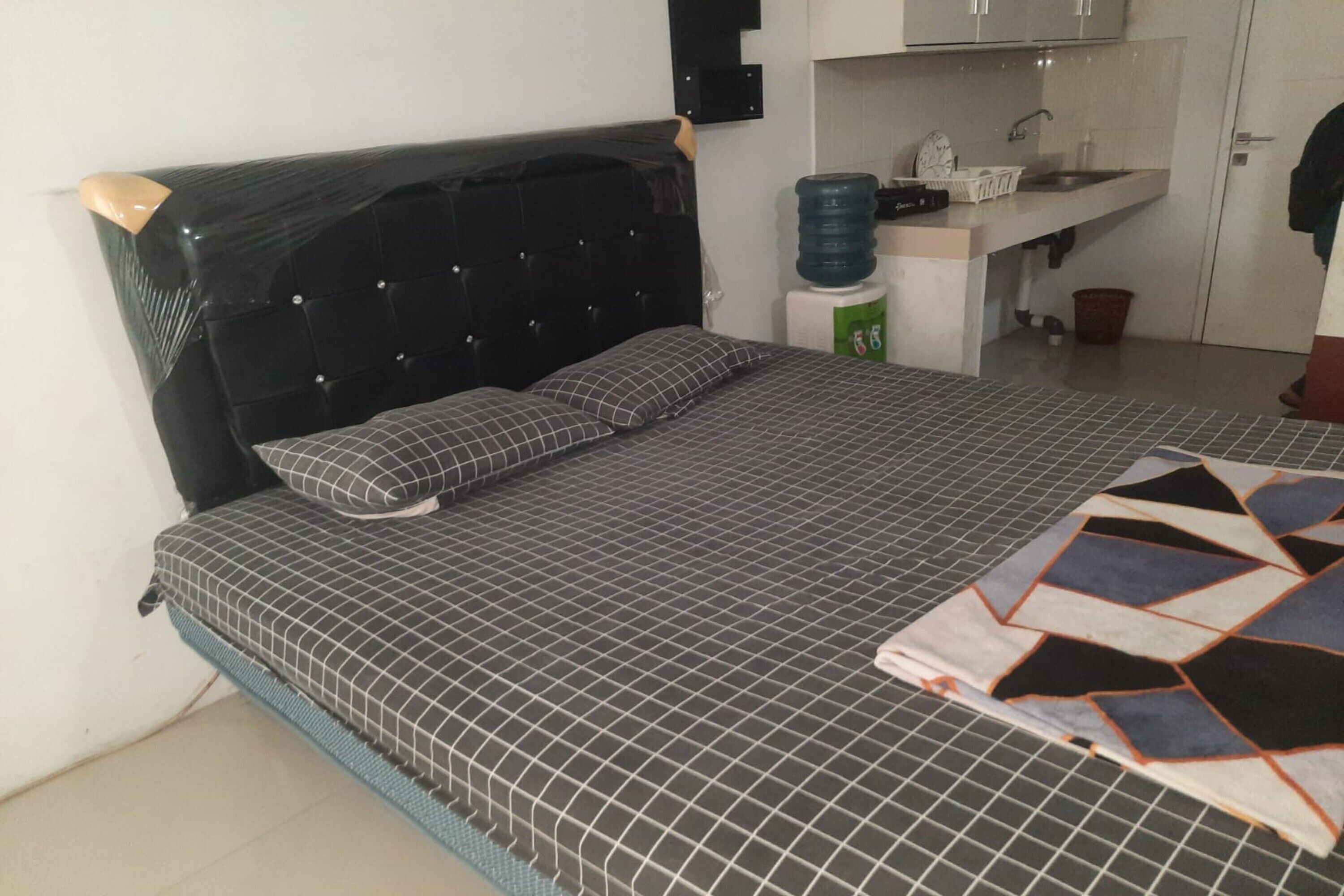 Un dormitorio con cama, dispensador de agua, lavamanos y armario.