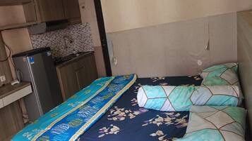 Un dormitorio con cama, una kitchenette pequeña y un armario de madera.