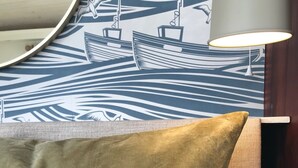 A bed with a headboard, a lamp, and a wall with a nautical-themed wallpaper. - Coastal chic in the heart of Kinsale (CO)