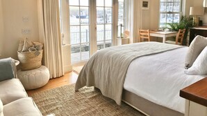 A bedroom with a large bed, a desk, and a view of the water through the window. - Coastal chic in the heart of Kinsale (CO)