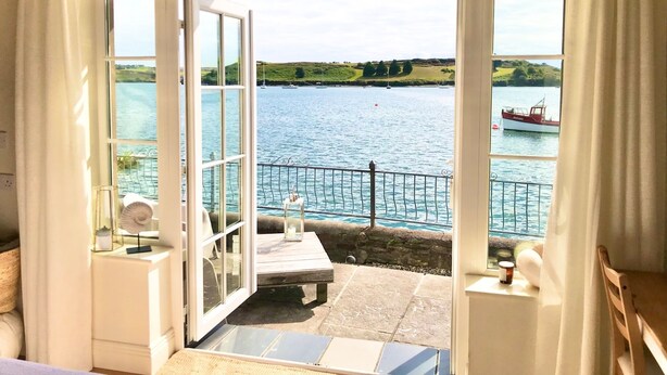 An open balcony with a view of a lake and boats, a wooden table, and a chair. - Coastal chic in the heart of Kinsale (CO)