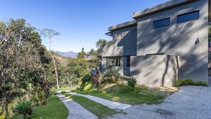 A modern house with a concrete exterior, a gravel driveway, and a pathway leading to the entrance.