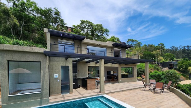 A modern two-story house with a swimming pool, outdoor seating area, and a covered patio.