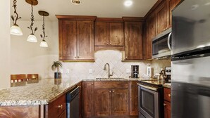 Eine Küche mit Holzschränken, einem Edelstahl-Kühlschrank, einer Mikrowelle und einer Arbeitsplatte aus Granit.