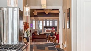 A modern kitchen with stainless steel appliances, a wooden island, pendant lighting, and a view into a living area with a sofa and a dining table. - The Historic Lyric Penthouse with Private Rooftop (Cincinnati)