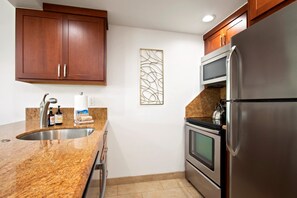 Una cocina con armarios de madera, un refrigerador de acero inoxidable, un microondas y un horno.