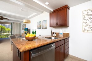Cocina moderna con encimeras de granito, lavavajillas, armarios de madera y un comedor con vista a zonas verdes.