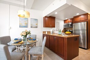 Una cocina moderna con armarios de madera, electrodomésticos de acero inoxidable y una mesa de comedor de vidrio con sillas.