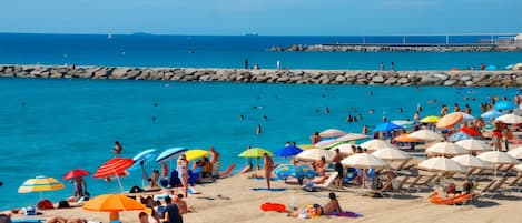 A crowded beach with numerous umbrellas and people sunbathing.
