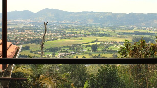 A view from a window overlooking a valley with mountains in the distance, a clear sky, and some greenery in the foreground. - Small cozy apartment surrounded by nature in the countryside of Bogotá (Bogotá)
