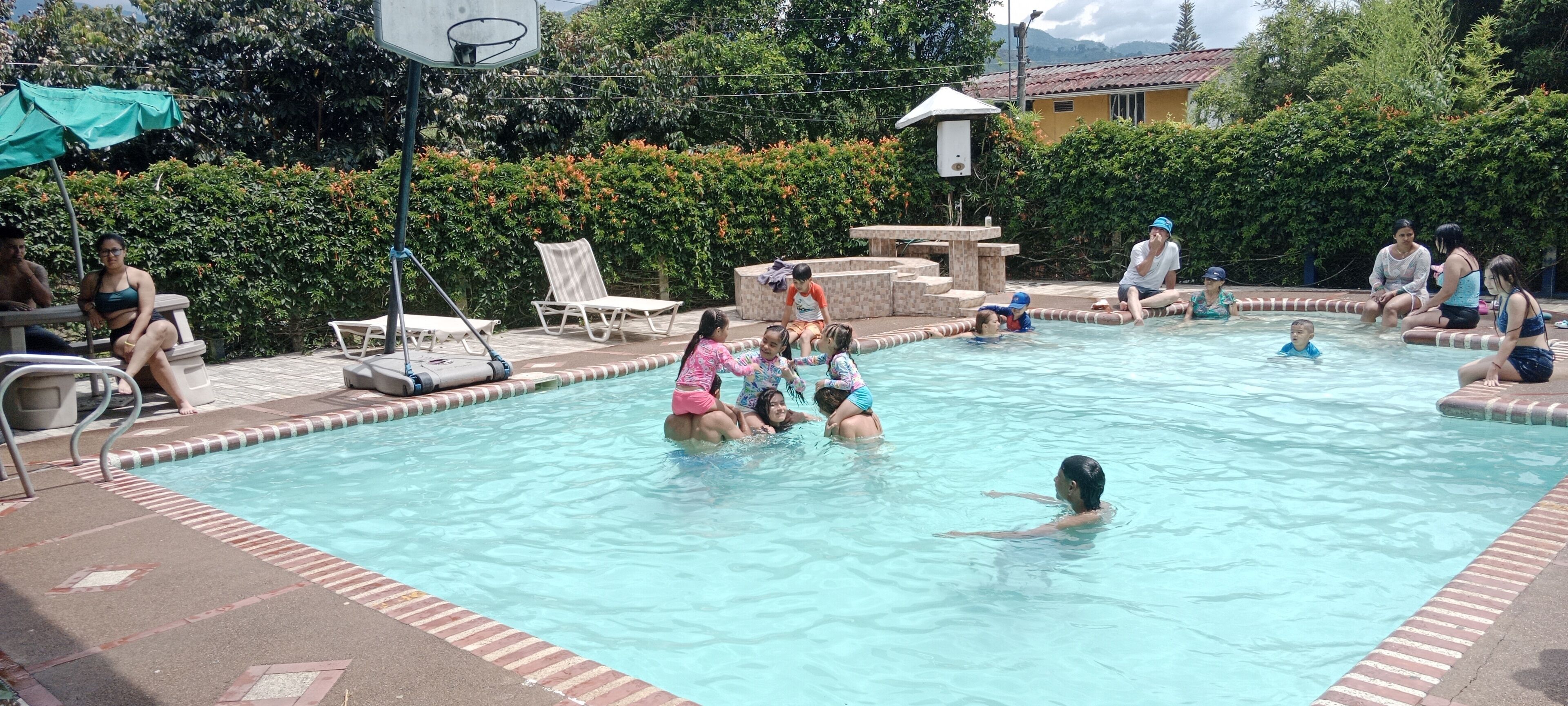 A swimming pool with people in the water and on the poolside.