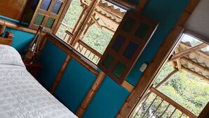 A room with a bed, a window with a view of greenery, and a wooden structure with a grid pattern. - cabañas hotel villa lucia (Calarcá)