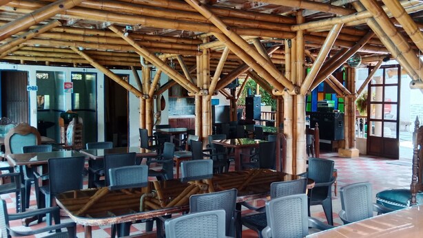 A restaurant with bamboo ceiling structures, tables, and chairs. - cabañas hotel villa lucia (Calarcá)